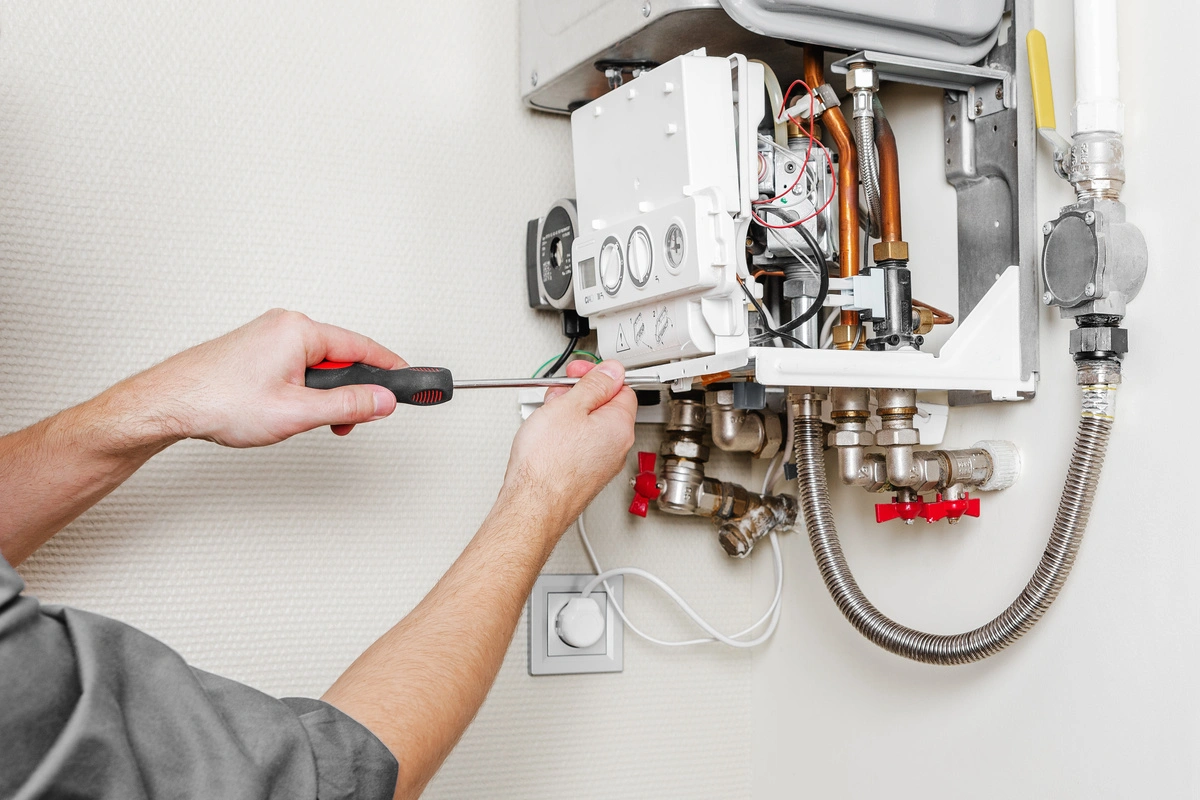 technicien effectuant l'entretien d'une chaudière murale à gaz