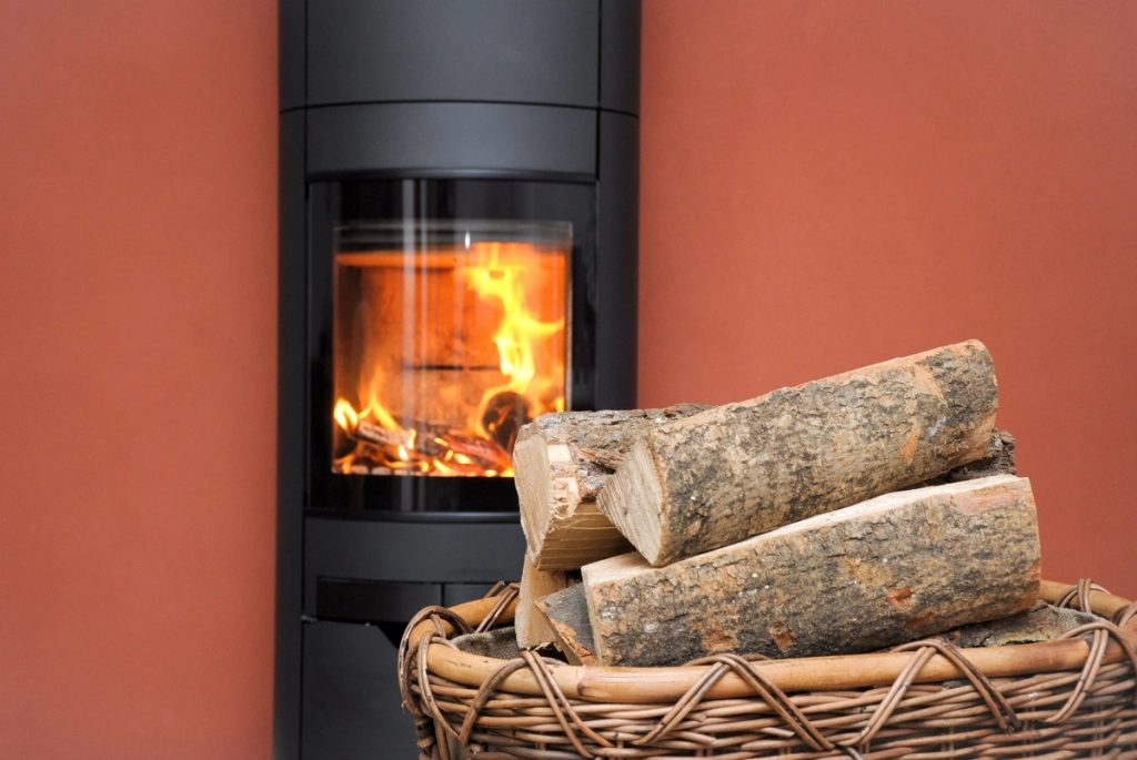Poêle à bois moderne en fonctionnement avec un panier de bûches de bois