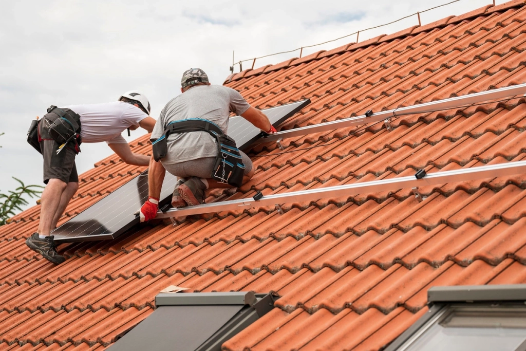 Techniciens installant des panneaux photovoltaïques sur un toit en tuiles